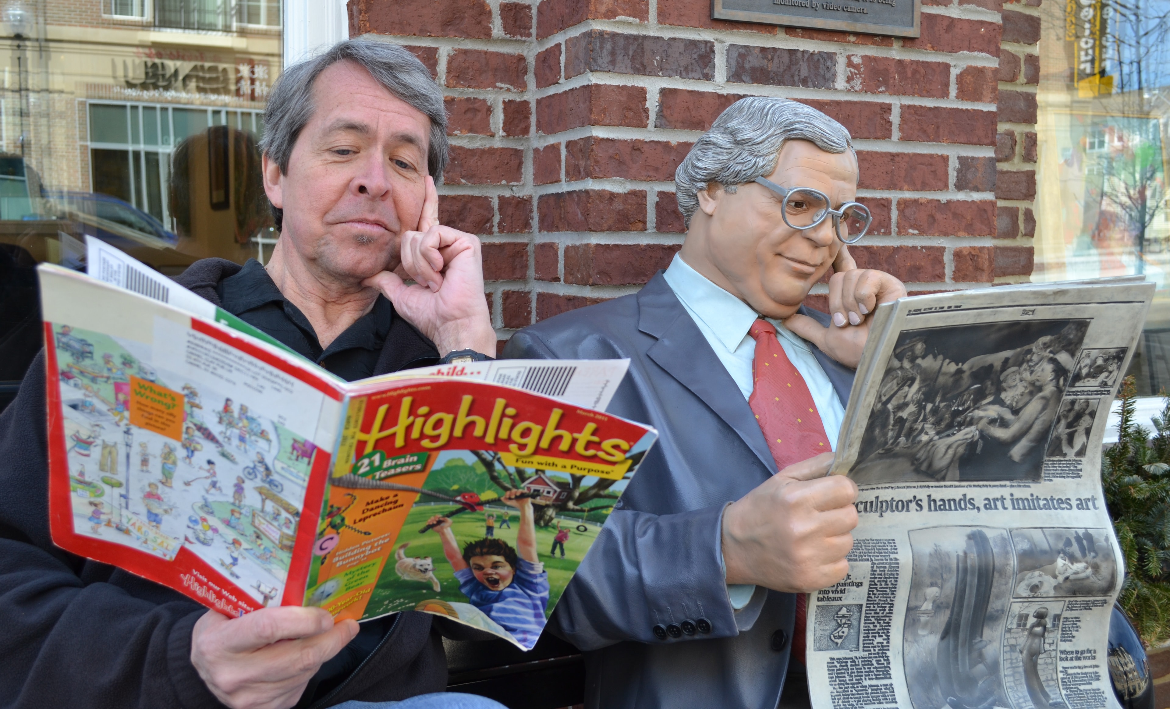 Dave Dugan reading Highlights magazine next to a statue doing the same pose